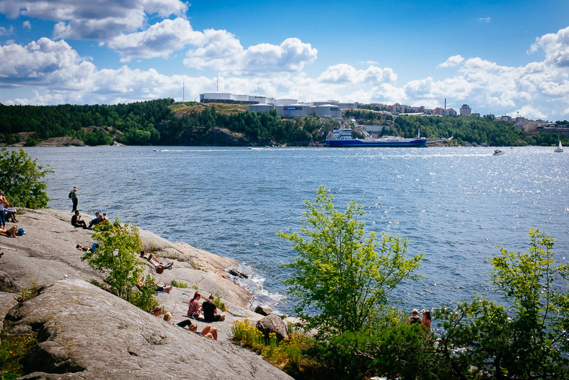 Locals relaxing on rocks near the water on Fjåderholmarna, a small getaway island near Stockholm.