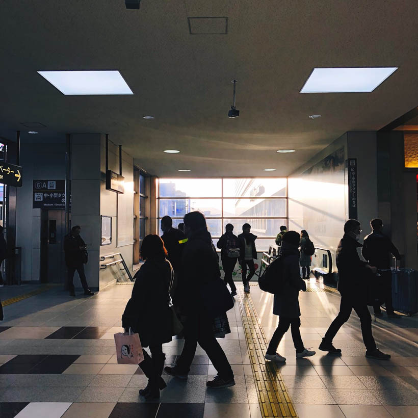 People walking through Kyoto station in Japan while the sun is setting.