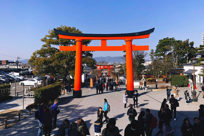 The crowded entrance of the Fushimi Inari Shrine in Kyoto, Japan, looking in the direction of the train station.