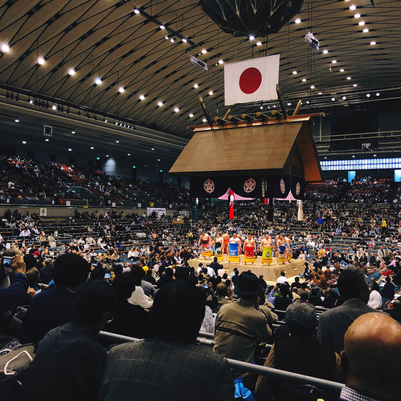 Sumo wrestlers doing an exhibition ceromony in the ring.