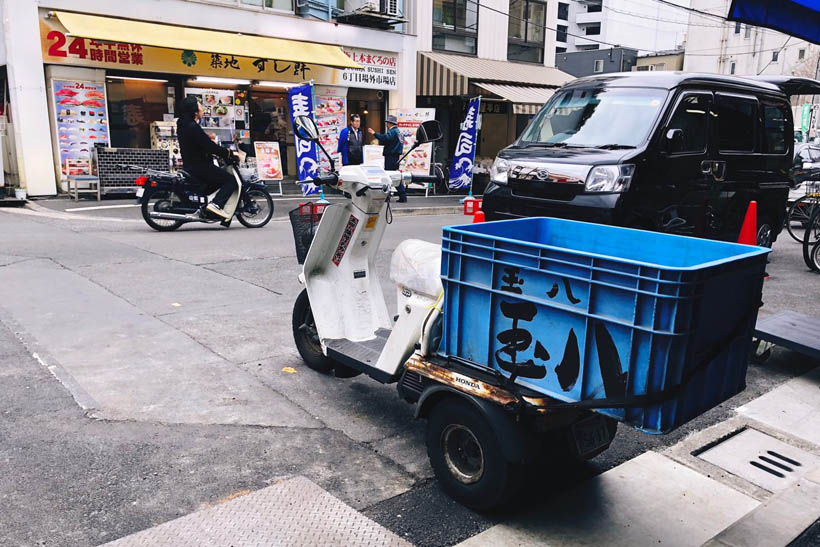 A parked scooter with a big blue box strapped to its back in the outer market of Tsukiji in Tokyo, Japan.